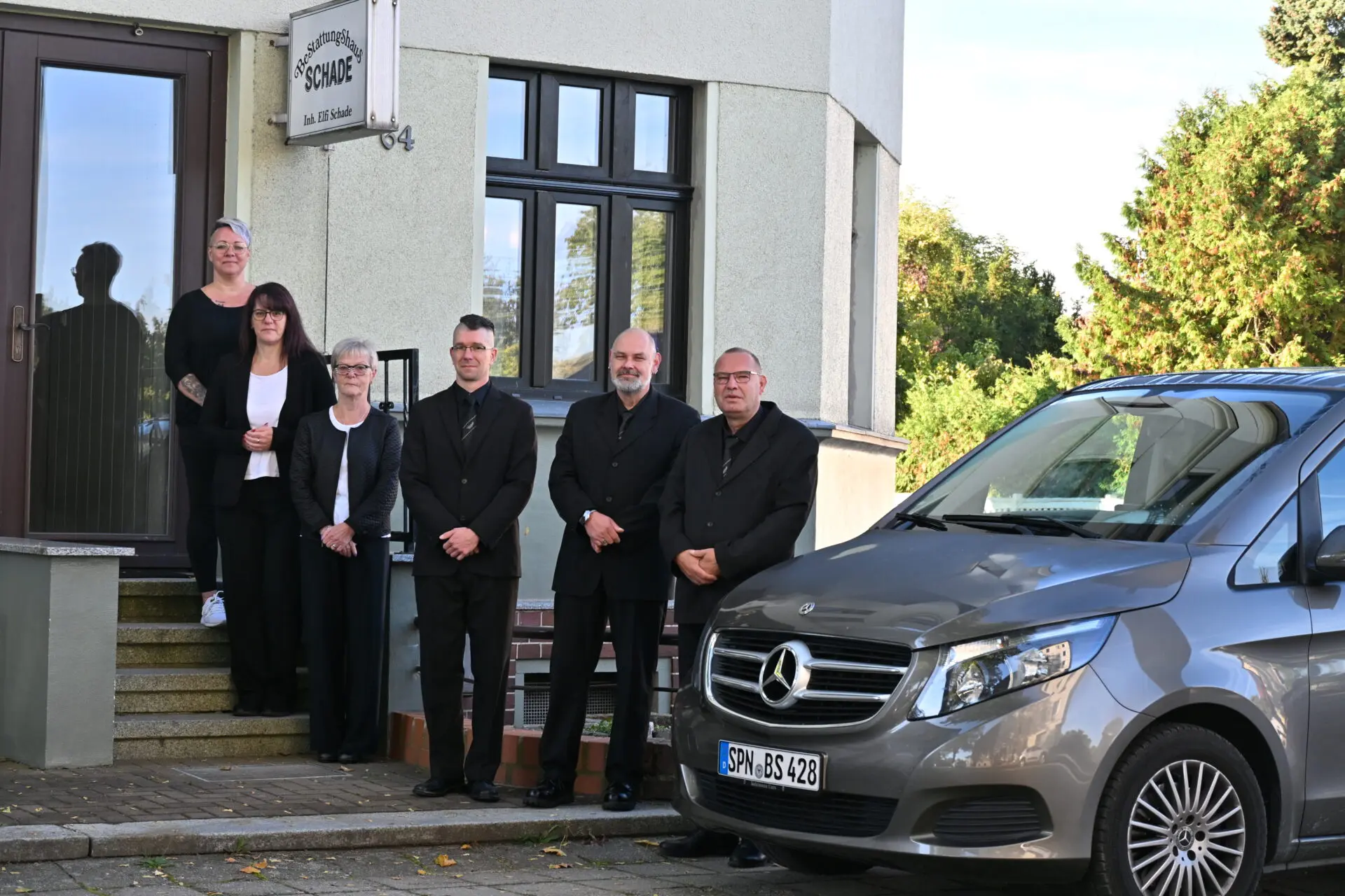 Team des Bestattungshauses Schade vor dem Firmengebäude mit Bestattungsfahrzeug