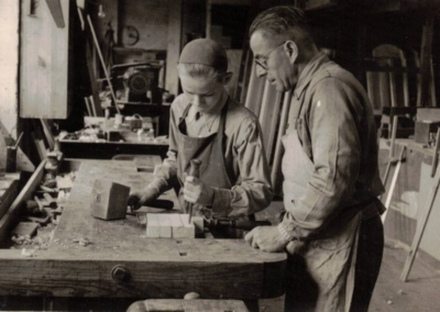Historische Aufnahme zweier Mitarbeiter des Bestattungshauses Schade bei handwerklichen Arbeiten in der Werkstatt.